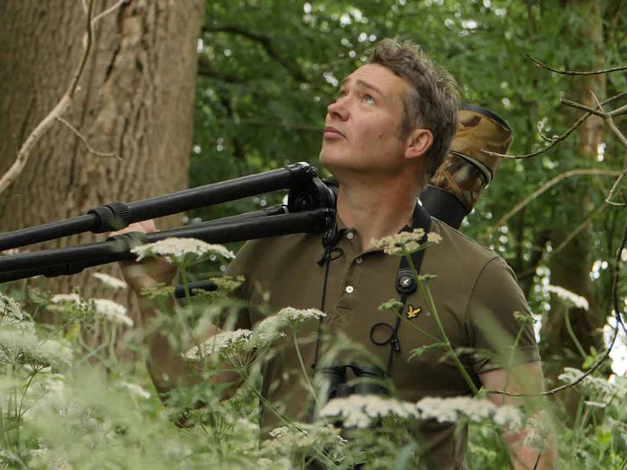 Yorkshire wildlife artist and filmmaker Robert E Fuller walking through woodland with camera over shoulder