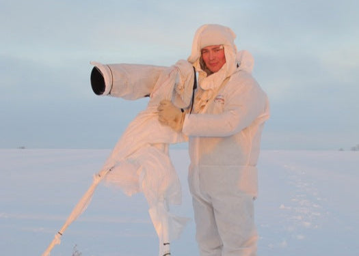 wildlife artist robert e fuller wearing camouflage with camera in snow field
