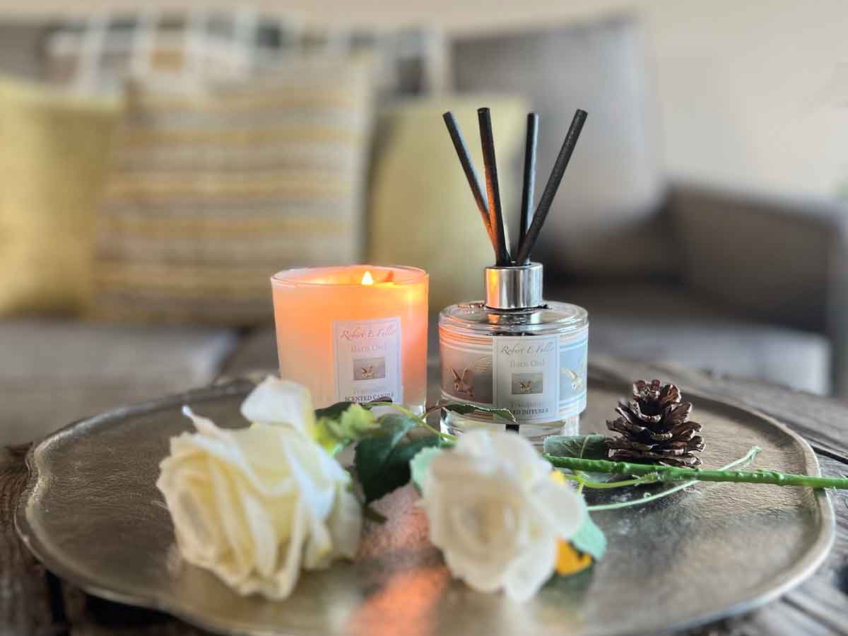 Candle and reed diffuser set on silver tray with roses and pine cone