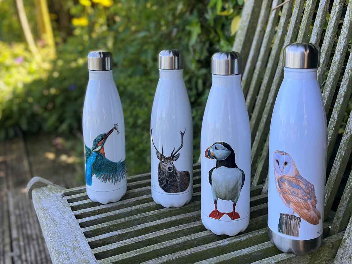 waterbottles with animal designs in row on garden seat with greenery behind